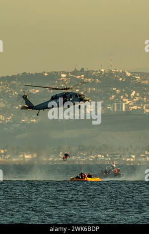 Un MH-60S Seahawk affecté aux « wildcards » du Helicopter Sea combat Squadron 23 simule la récupération du personnel pendant la formation de récupération maritime dans la baie de San Diego, le 14 février 2024. Des marins attachés au quai de transport amphibie USS San Diego (LPD 22), à l’unité de soutien expéditionnaire 1 de l’élimination des engins explosifs et au Helicopter Sea combat Squadron 23 « Wildcards » se sont entraînés aux côtés de la NASA avant le test de récupération 11 en cours. En préparation de la mission Artemis II de la NASA, qui enverra quatre astronautes à Orion au-delà de la Lune, la NASA et le ministère de la Défense effectueront une série de tests Banque D'Images