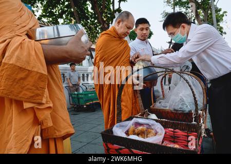 Au cours de leur traditionnelle ronde matinale à Bangkok, en Thaïlande, les moines bouddhistes thaïlandais reçoivent des sacs de nourriture par des laïcs aisés Banque D'Images