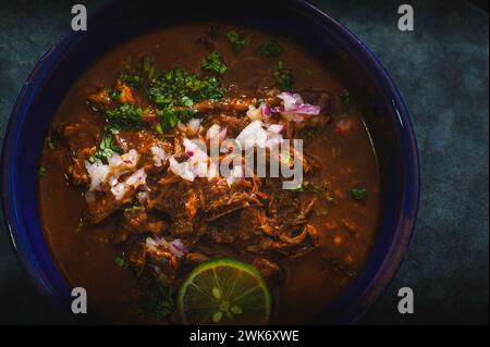 Bol de ragoût de bœuf mexicain Birria sur fond bleu Banque D'Images