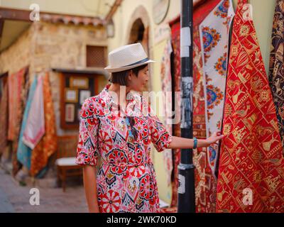 Voyage d'été féminin à Antalya, Turquie. Jeune femme asiatique en robe rouge marcher vieille ville Kalechi , touriste femme découvrir des endroits intéressants et attraction touristique populaire, regarder sur capret Banque D'Images