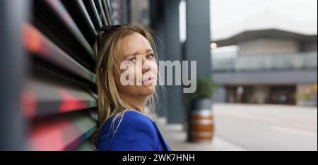 Portrait de belle femme d'affaires debout devant l'immeuble de bureaux dans la ville. Blazer bleu, tenue professionnelle décontractée pour le travail. Bannière avec copysp Banque D'Images