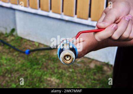 Robinet à boisseau sphérique en laiton avec un levier d'activation est connecté au tuyau PE à l'aide d'un adaptateur fileté en plastique. Banque D'Images