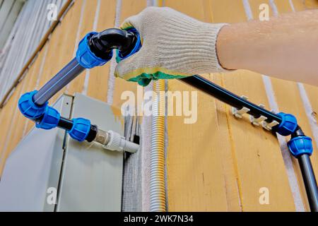 Les raccords de compression coudés sont utilisés pour installer la plomberie externe pour l'eau potable et l'irrigation, le plombier serre l'écrou pour engager la pince à collet. Banque D'Images