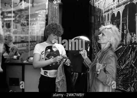 Vivienne Westwood portant une veste en feutre Inside Out dans sa boutique Seditionaries dans le Kings Road Chelsea. Les assistants de magasin Michael Collins qui porte le T-shirt Cambridge Rapist design, produit par Malcolm McLaren, partenaire de Westwood, quelques années plus tôt. Chelsea, Londres, Angleterre 1977 1970s UK HOMER SYKES Banque D'Images