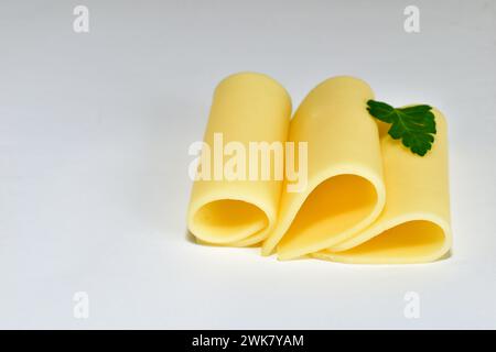 Trois morceaux de fromage en forme de plaques torsadées reposent sur un fond blanc. Banque D'Images