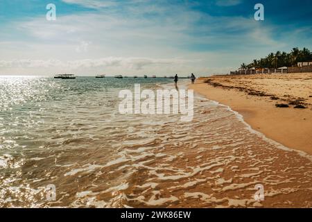 Vue arrière d'un homme et d'une femme marchant sur la plage de Malindi Beach dans le parc national marin de Malindi, Kenya Banque D'Images