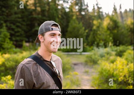 Homme souriant avec chapeau dans le cadre de la forêt Banque D'Images