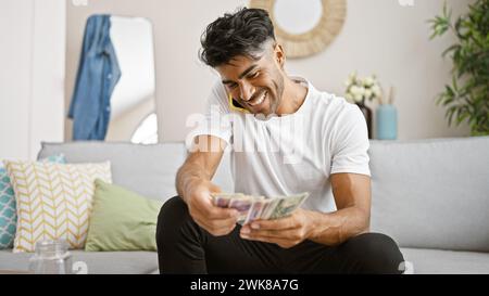 Un jeune homme hispanique joyeux compte du zloty polonais à la maison. Banque D'Images