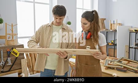 Un homme et une femme examinent le bois ensemble dans un atelier de menuiserie lumineux Banque D'Images