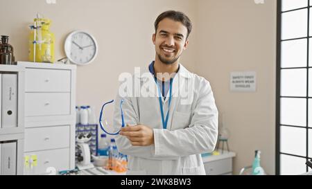 Beau jeune homme en blouse de laboratoire souriant à l'intérieur dans un laboratoire moderne Banque D'Images