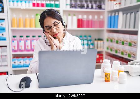 Jeune femme arabe travaillant à la pharmacie à l'aide d'un ordinateur portable dormant fatigué rêver et poser avec les mains ensemble tout en souriant avec les yeux fermés. Banque D'Images