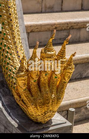 Une naga dorée à cinq têtes, ou divinité de l'eau, sur les marches de Phra Mondhop dans le complexe du Grand Palais à Bangkok, en Thaïlande. Banque D'Images