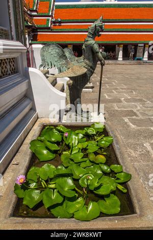 Statue en bronze d'un oiseau Tantima mythique et nénuphars en fleurs dans le complexe du Grand Palais à Bangkok, Thaïlande. Banque D'Images