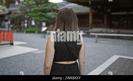 Belle femme hispanique brune dans des verres, s'éloignant lors d'une promenade décontractée à fushimi inari-taisha, le sanctuaire sacré de kyoto du japon, une vie passionnante Banque D'Images