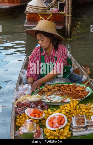 Une femme thaïlandaise préparant de la nourriture sur son bateau dans le Damnoen Saduak Floating Market en Thaïlande. Banque D'Images