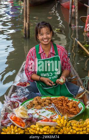 Une femme thaïlandaise préparant de la nourriture sur son bateau dans le Damnoen Saduak Floating Market en Thaïlande. Banque D'Images