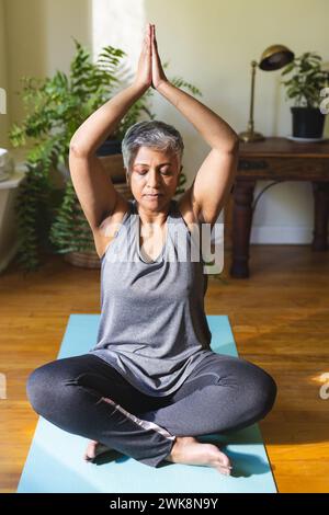 Une femme biraciale mature pratique le yoga à la maison Banque D'Images