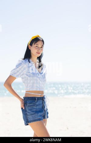 Jeune femme biraciale pose sur une plage ensoleillée, avec un espace de copie Banque D'Images