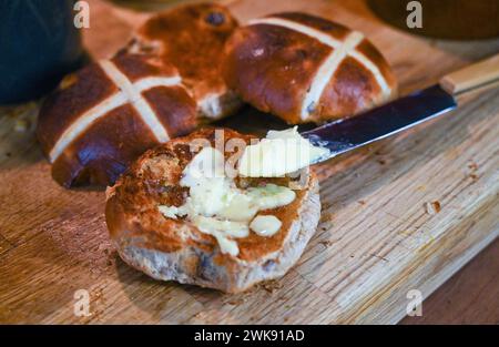 Brioches Hot Cross grillées au beurre un plat traditionnel du petit déjeuner mangé à Pâques Banque D'Images