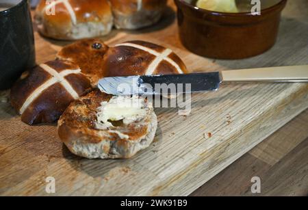 Brioches Hot Cross grillées au beurre un plat traditionnel du petit déjeuner mangé à Pâques Banque D'Images