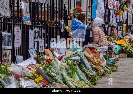 Londres, Royaume-Uni. 19 février 2024. Un couple est assis à côté de fleurs et d'hommages pour Alexei Navalny au mémorial de fortune en face de l'ambassade de Russie à Londres après la mort du leader de l'opposition dans une prison en Russie. Crédit : SOPA images Limited/Alamy Live News Banque D'Images