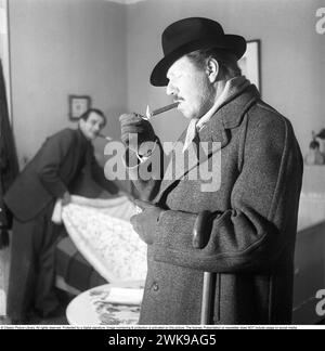 Fumer un cigare 1949. L'acteur Åke Fridell allume un cigare. Notez le détail de lui portant une bande de deuil noire sur son manteau. Kristoffersson ref AN27-5 *** local Caption *** © Classic Picture Library. Tous droits réservés. Protégé par une signature numérique. La surveillance et la protection de l'image sont activées sur cette image. La licence ; présentation ou newsletter N'inclut PAS l'utilisation sur les médias sociaux. Banque D'Images