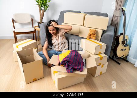 Une jeune femme fatiguée, épuisée par le déménagement et le transport de biens dans une nouvelle maison Banque D'Images