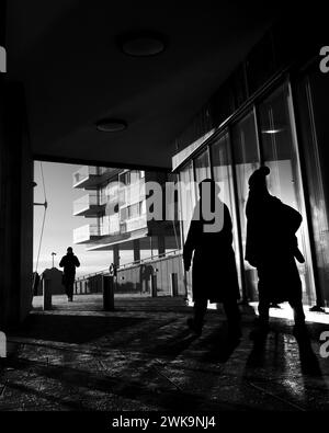 Les gens marchant dans une rue ensoleillée en niveaux de gris Banque D'Images