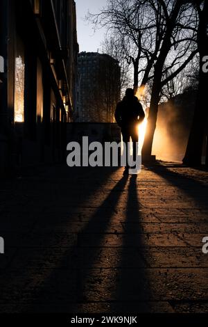 Une silhouette d'une personne marche sur une rue ensoleillée à l'heure dorée Banque D'Images
