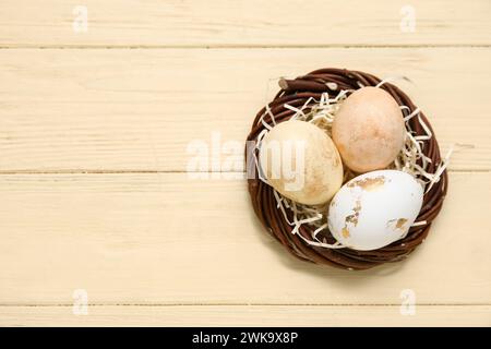 Nid avec des oeufs de Pâques peints sur fond en bois jaune Banque D'Images