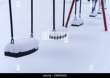 Gros plan des balançoires couvertes de neige sur le terrain de jeu vide en hiver. Finlande. Banque D'Images