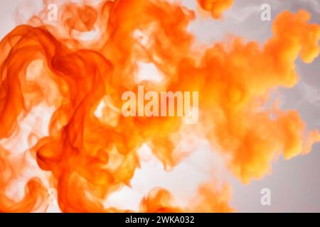 Une image floue de bouffées orange de fumée et de peinture acrylique dissoute dans l'eau. Banque D'Images