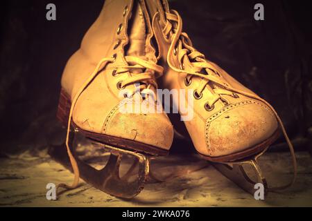 Vieux patins vintage, minables et usés sur un fond enneigé de teinte marron. Banque D'Images