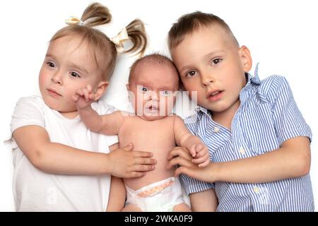 Frère et sœur sont allongés avec un nouveau-né. Trois petits enfants d'âges différents. Les enfants dans la famille. Banque D'Images