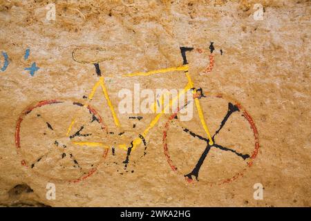 Peinture sculptée de vélo de course sur le mur de la grotte préhistorique, Albufeira, région de l'Algarve, Portugal. Banque D'Images