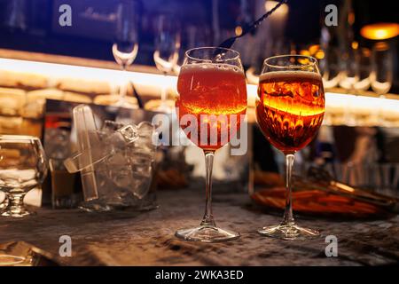 Deux verres de cocktail Aperol spritz sur le comptoir du bar. Préparation de boissons alcoolisées italiennes typiques, apéritif à base de vin blanc mousseux Prosecco, glace Banque D'Images