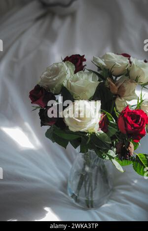 Un mini vase avec des roses rouges, blanches et violettes Banque D'Images