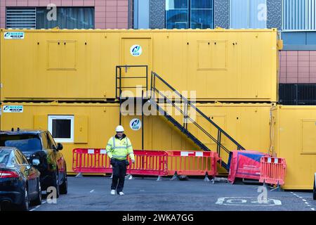 Cabines temporaires de grands constructeurs jaunes créant des formes abstraites avec travailleur en veste haute viz et casque de sécurité à Leyden Street Aldgate Londres Angleterre Banque D'Images