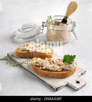 Pâté maison, tartinade ou mousse dans un bocal en verre avec du pain tranché et des herbes Banque D'Images