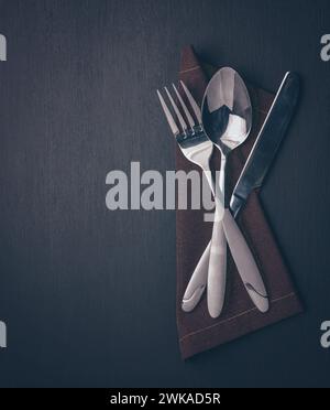 couverts set-fourchette, cuillère, couteau, sur bois foncé. Nature morte minimaliste, vaisselle élégante. gros plan de la décoration de la cuisine et du set de table. Top vie Banque D'Images