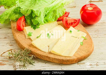 Tranches de fromage, tomates et laitue sur une planche à découper en bois Banque D'Images