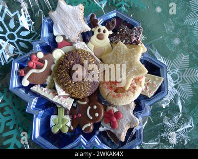 Biscuits festifs de vacances dans un plat bleu en forme d'étoile, prêt à être enveloppé dans une pellicule de cellophane avec un motif de flocon de neige. Banque D'Images