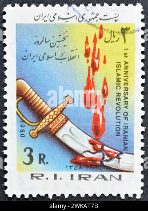 Timbre-poste oblitéré imprimé par l'Iran, qui montre une dague et du sang coulant, 1er anniversaire de la révolution islamique, vers 1980. Banque D'Images