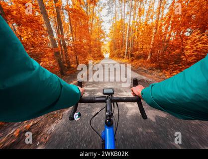 POV photo d'un cycliste conduisant un vélo de route au milieu d'une forêt d'automne par temps ensoleillé. Banque D'Images