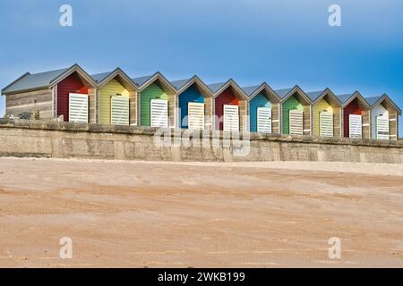 Cabanes de plage aux couleurs vives debout sur une promenade en bord de mer Banque D'Images