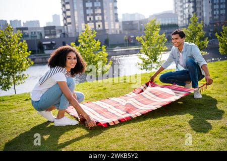 Portrait en taille réelle de deux beaux partenaires positifs posés couverture de pique-nique à carreaux herbe verte passer du temps libre air frais à l'extérieur Banque D'Images