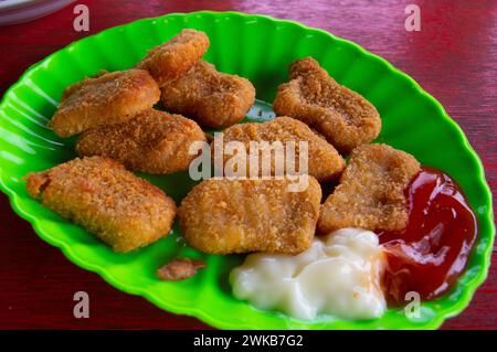 nuggets sur une assiette verte qui repose sur une table en bois Banque D'Images