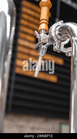 Gros plan d'un robinet de bière brillant sur un fond flou au bar-pub de la brasserie. Banque D'Images