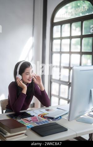 Graphiste femmes freelance portant casque à écouter de la musique à la détente après avoir esquissé la marque de logo et travailler à la conception sur le graphique Banque D'Images