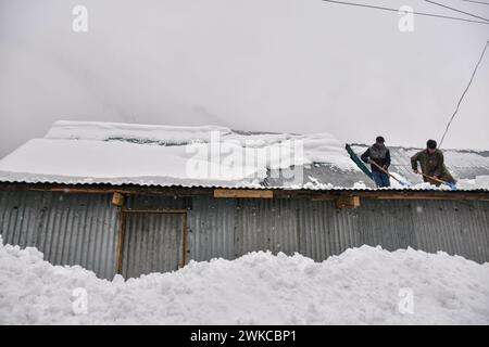 Gaganfir, Inde. 19 février 2024. Les hommes cachemiris dégagent la neige du toit après de fortes chutes de neige à Gagangir, à environ 90 km de Srinagar. De fortes chutes de neige et de fortes pluies au Cachemire ont coupé la vallée du reste du monde. Toutes les autoroutes sont fermées à la circulation. Le météorologue a prévu que la pluie et la neige continueront pendant encore 48 heures, ce qui pourrait entraîner de légères chutes de neige dans les plaines de la vallée. Crédit : SOPA images Limited/Alamy Live News Banque D'Images